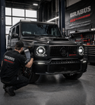 Black BRABUS vehicle in a garage with a person working on it, featuring BRABUS branding.