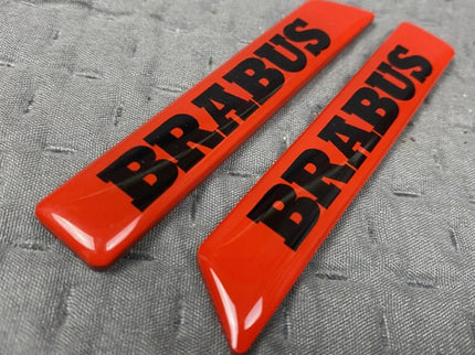 Two red 'BRABUS' logos on a gray textured background