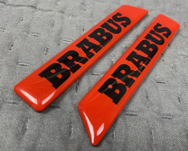 Two red 'BRABUS' logos on a gray textured background