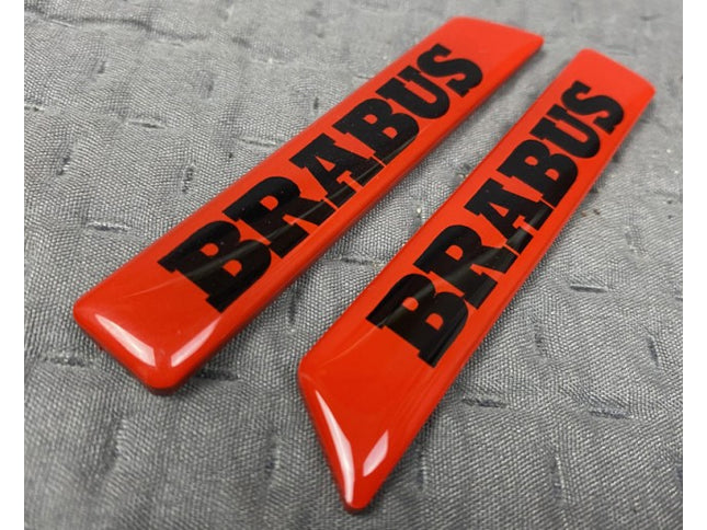 Two red 'BRABUS' logos on a gray textured background