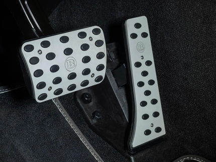 Car pedals with branded踏板 on a black floor mat