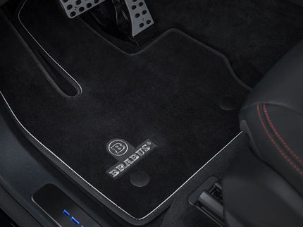 Car interior with black floor mats featuring a brand logo.