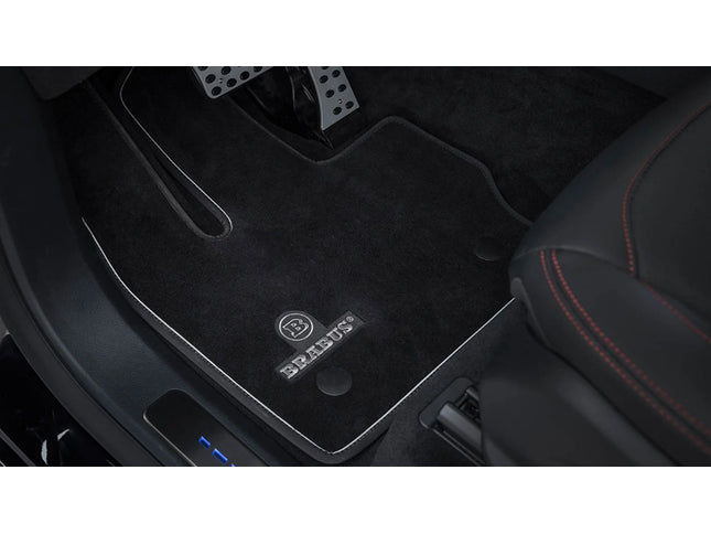 Car interior with black floor mats featuring a brand logo.