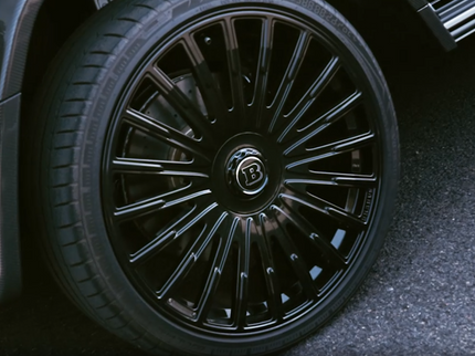 Close-up of a car wheel with a detailed rim design on a dark surface.