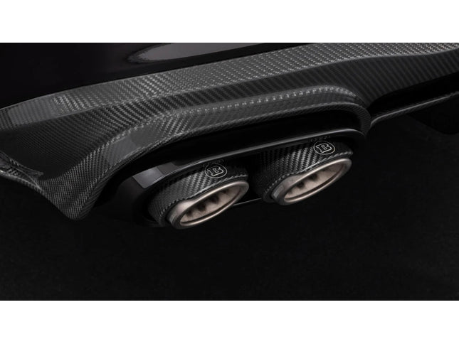 Close-up of a car's carbon fiber exhaust system with a prominent brand logo on a dark background.